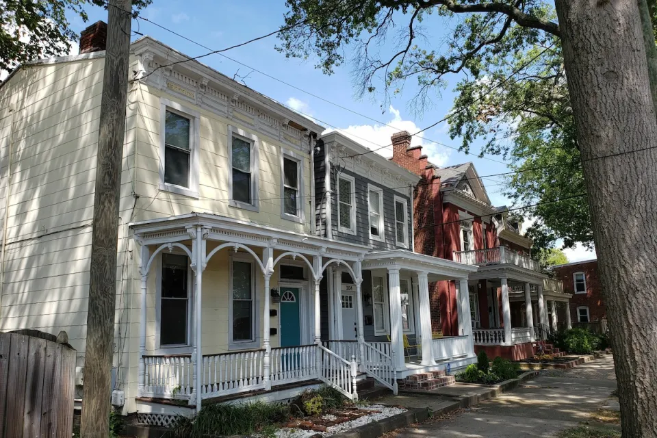Historic homes with intricate white trim on tree-lined street in Richmond, Virginia.